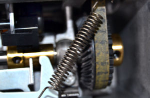 Close up of the guts of a sewing machine - loose spring
