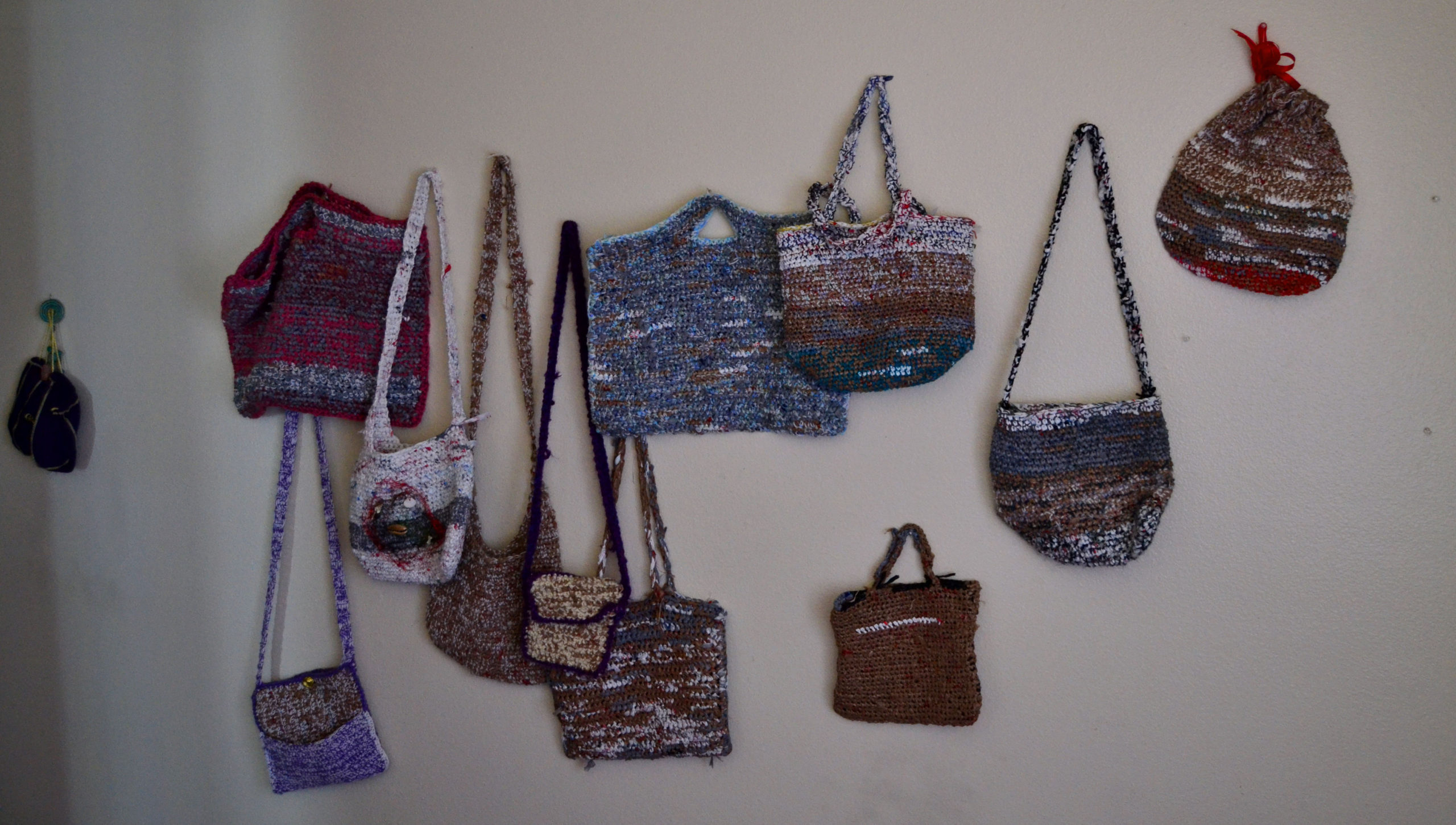 a variety of hand-crocheted bags and purses made from recycled plastic shopping bags