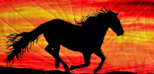 Black stallion running wild against red, orange, and gold sunset backdrop fabric magic quilt