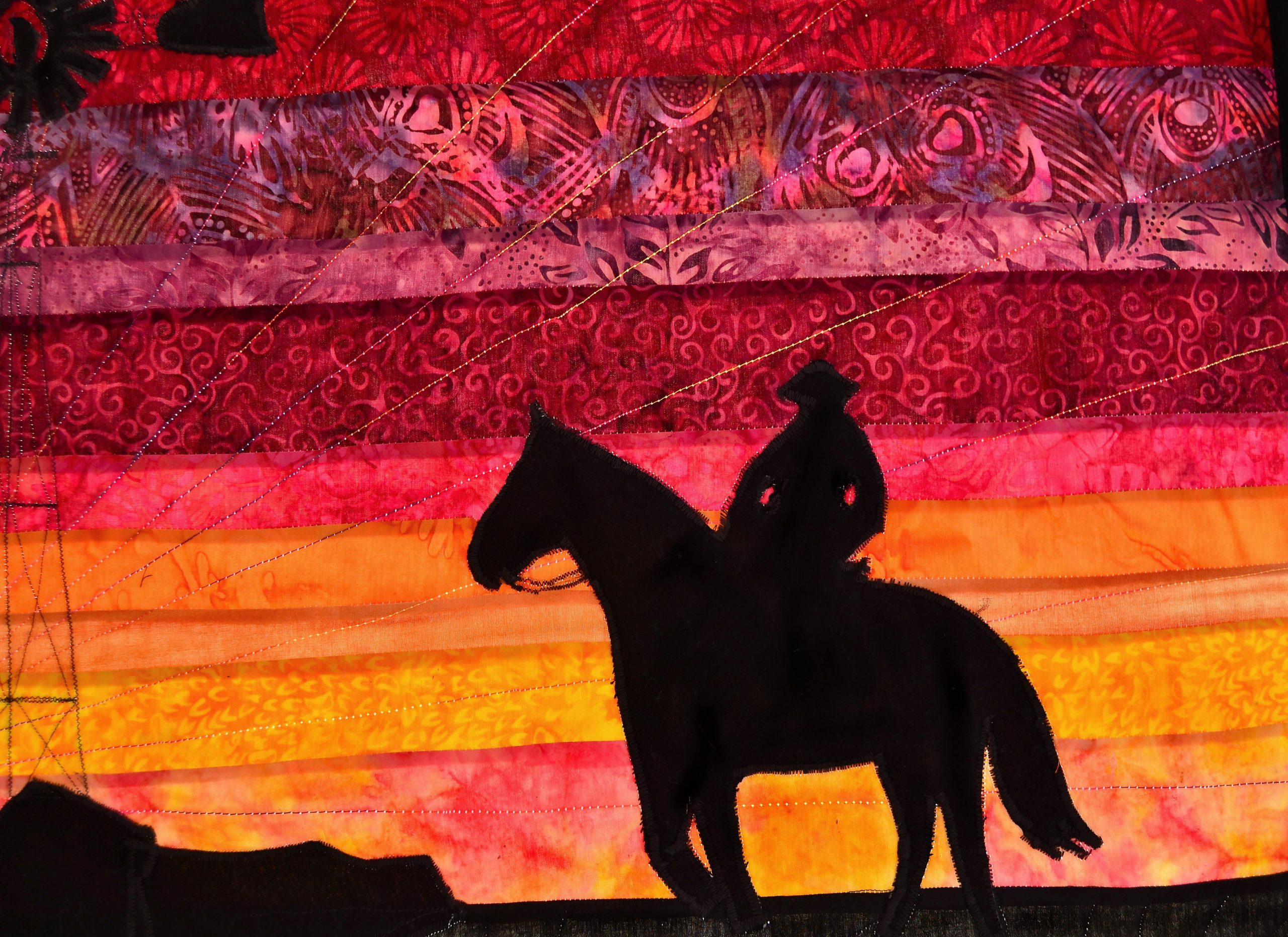 Cowboy on a horse against a sunset made of beautiful batik fabrics ranging dark pink to bright orange
