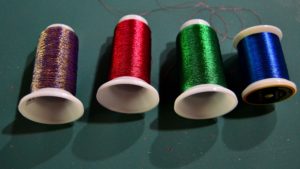 Large spools of metallic thread in purple, red, green, and blue