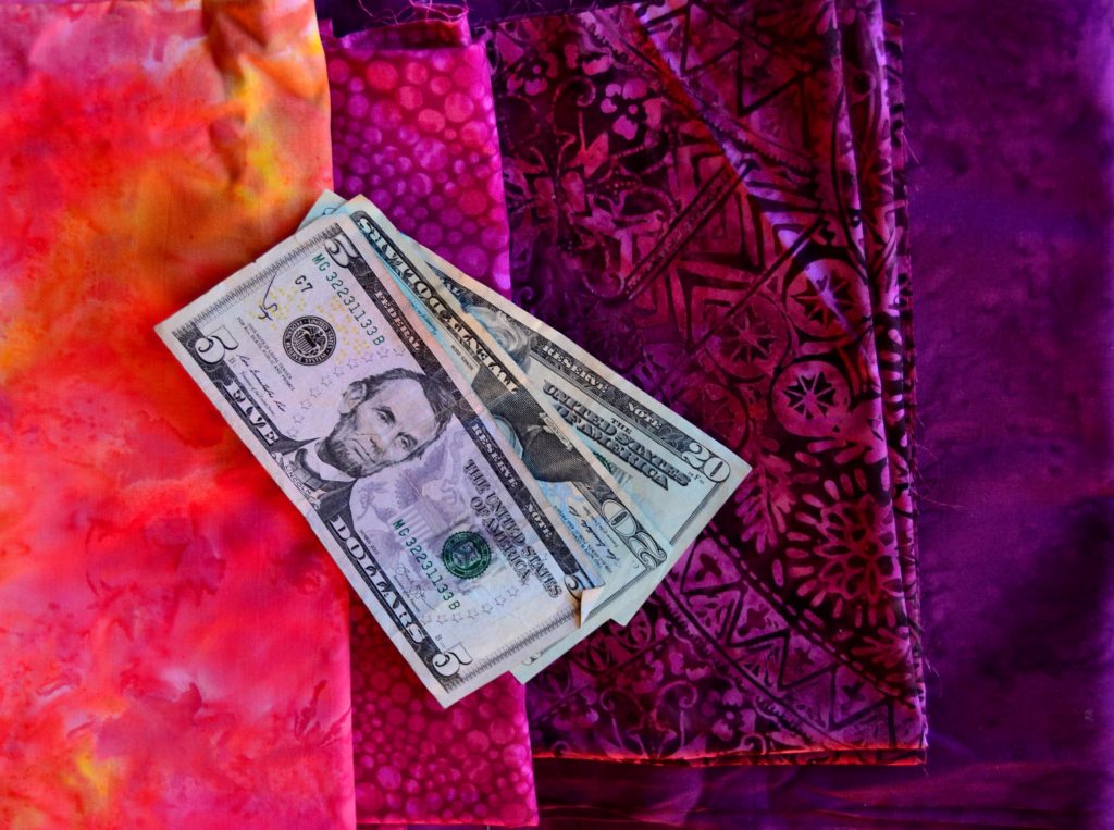 2 20 dollar bills and a 5 on a background of purple-to-pink fabrics sewing within your means illustration