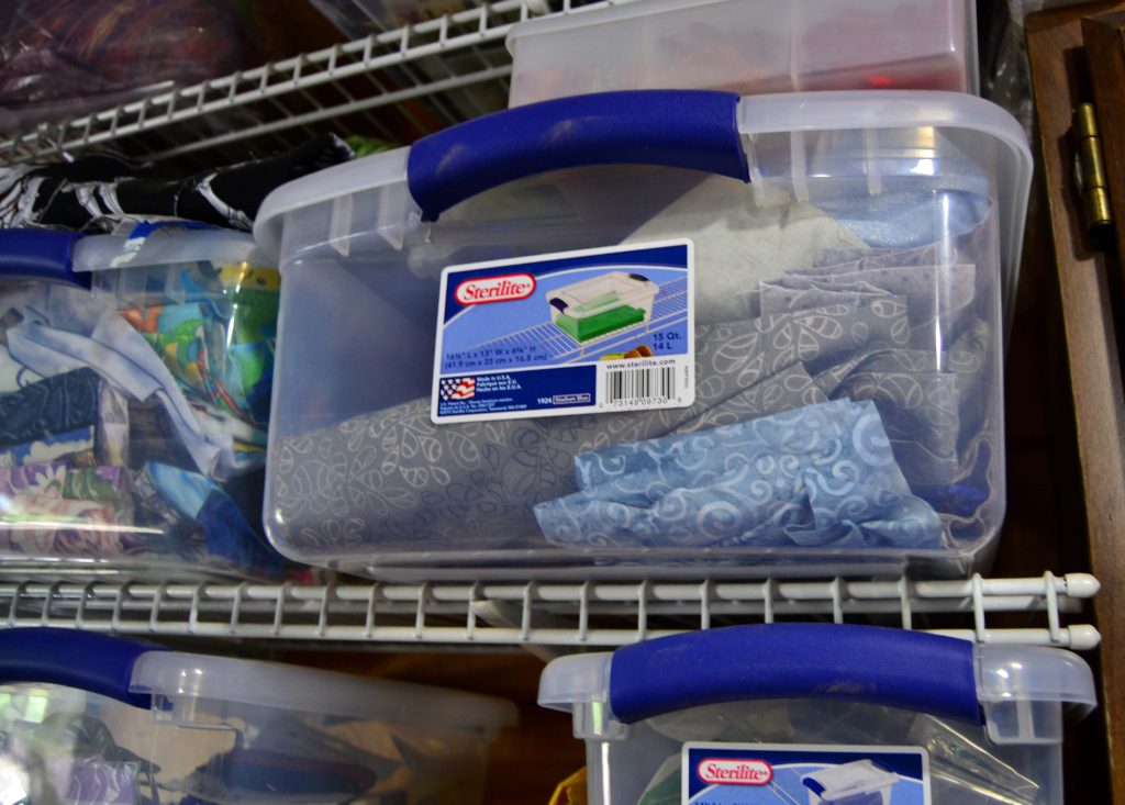 Large plastic tub full of color-themed grey and silver fabric