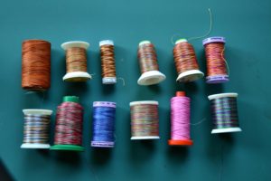 Two rows of different variegated threads on different sized spools - beautiful, vibrant colors