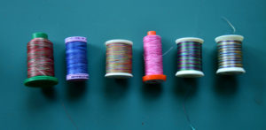 Four variegated thread spools in blues and pinks