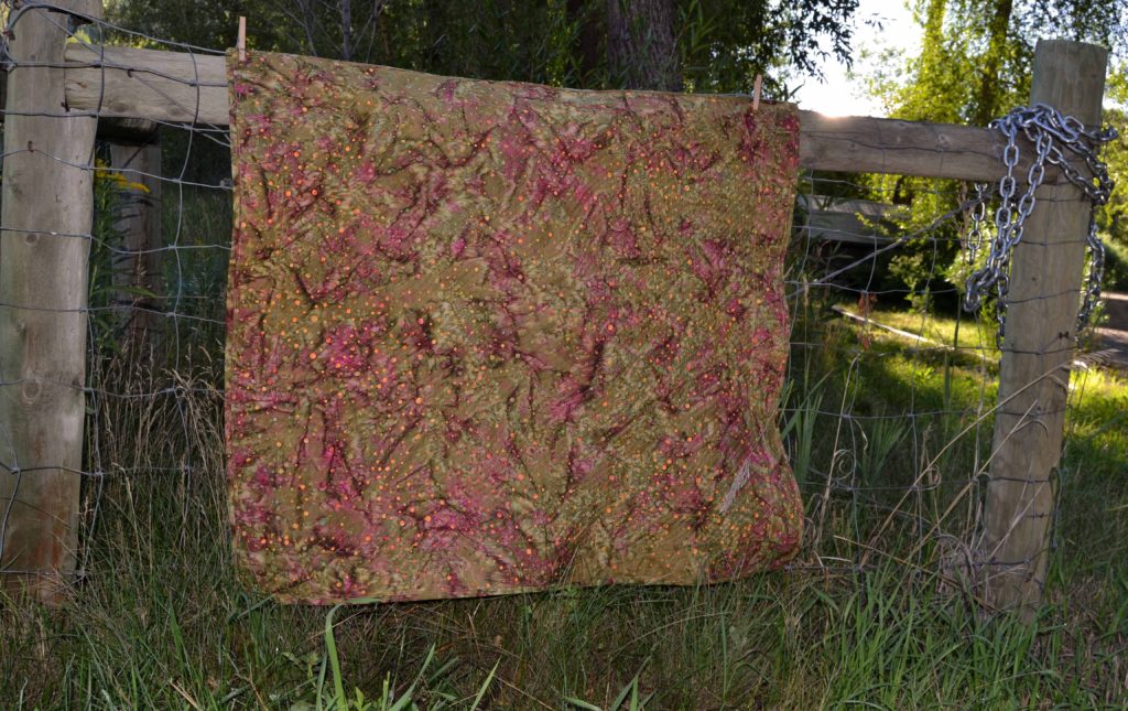 Mottled earth tones quilt backing over a country fence