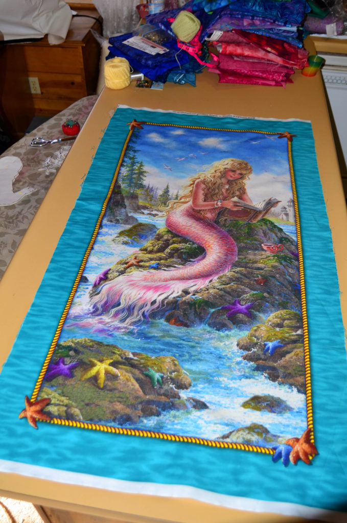 Mermaid reading by the shore - an example of a fabric panel for quilting