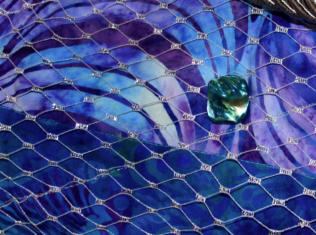 Bead in the middle of a turquoise and purple background, right in the middle of a quilting project