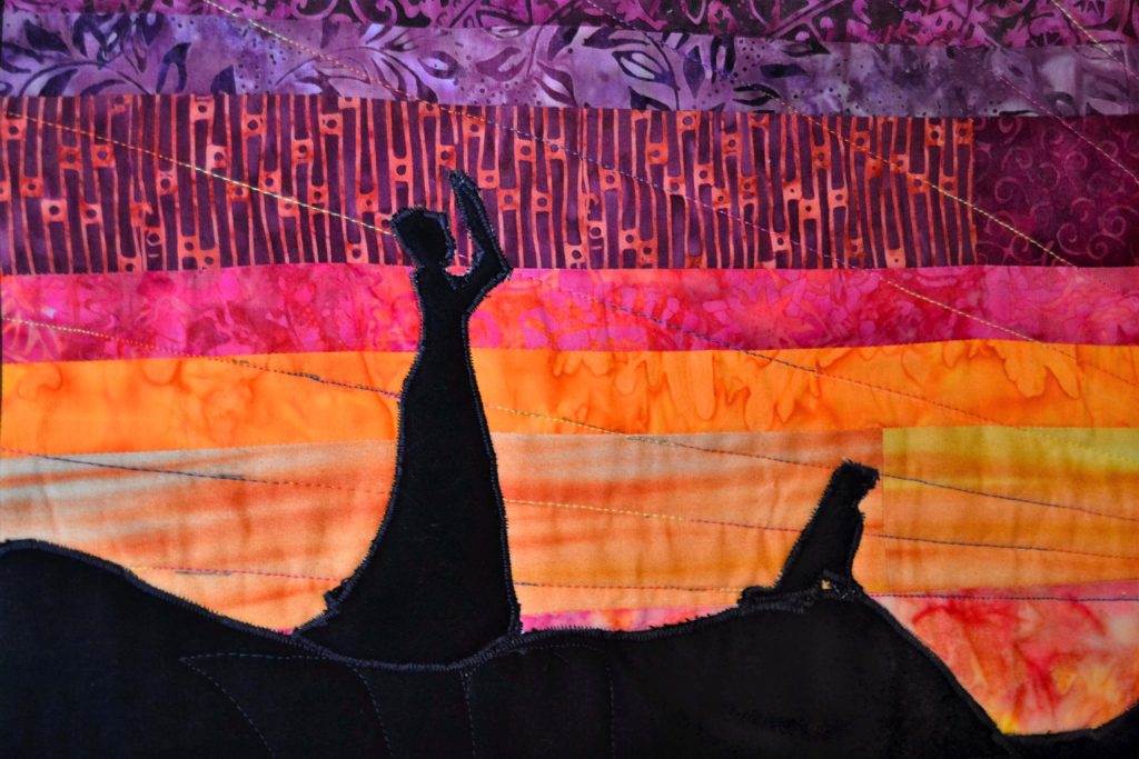 A western lady and a dog against a sunset - quilted using free motion quilting techniques