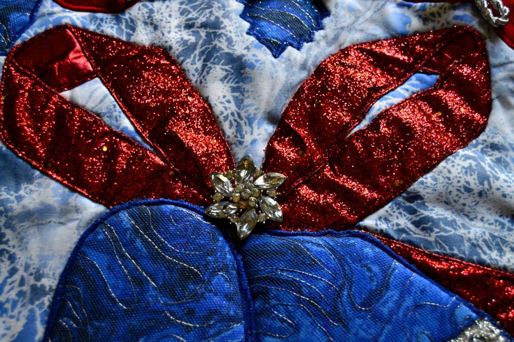 Art salvage button that finishes a red bow on blue Christmas bells