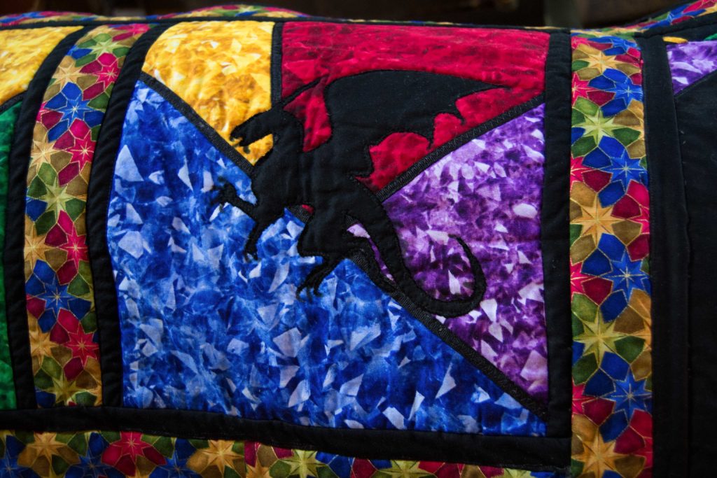 Black dragon silhouette on stained glass window creating quilting stories