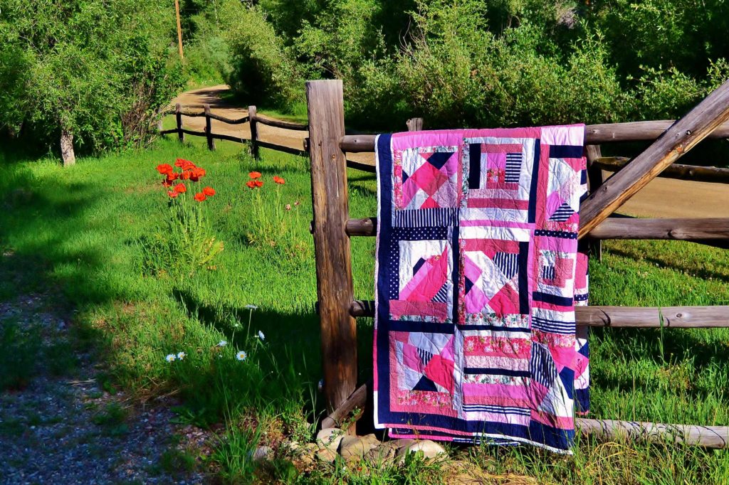 Nazca Lines - how to sew binding on a quilt - pink navy and white quilt on country gate