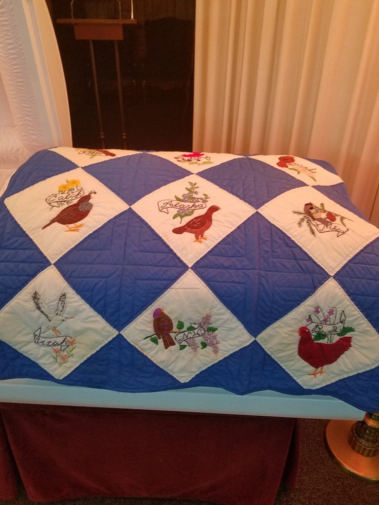Embroidered 50 birds of the US quilt over Granny's coffin